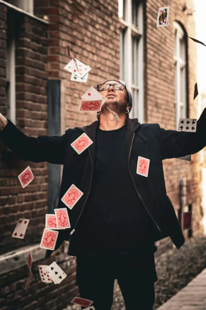 Tripp throwing a full deck of cards into the air in a brick alley